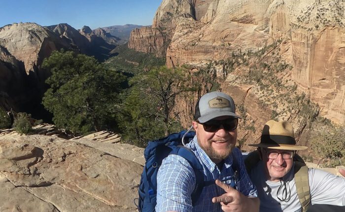 A guide and guest pose for a photo at the top of Angel's Landing in Zion National Park, Utah. Taken on a Teton Excursions tour of Utah's Mighty 5 National Parks.