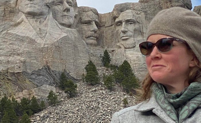 A woman poses alongside Mount Rushmore.