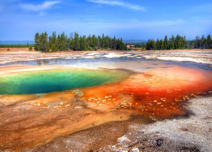 Hot Spring pool in Yellowstone National Park. A couple watches as Old Faithful geyser erupts in Yellowstone National Park. Taken on a Teton Excursions tour of Yellowstone National Park.