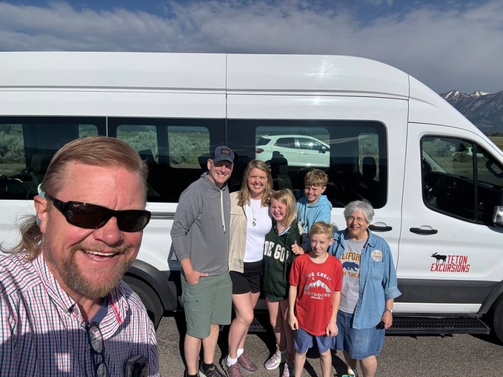 Guests posing for a photo beside the private tour van before a Yellowstone day tour.